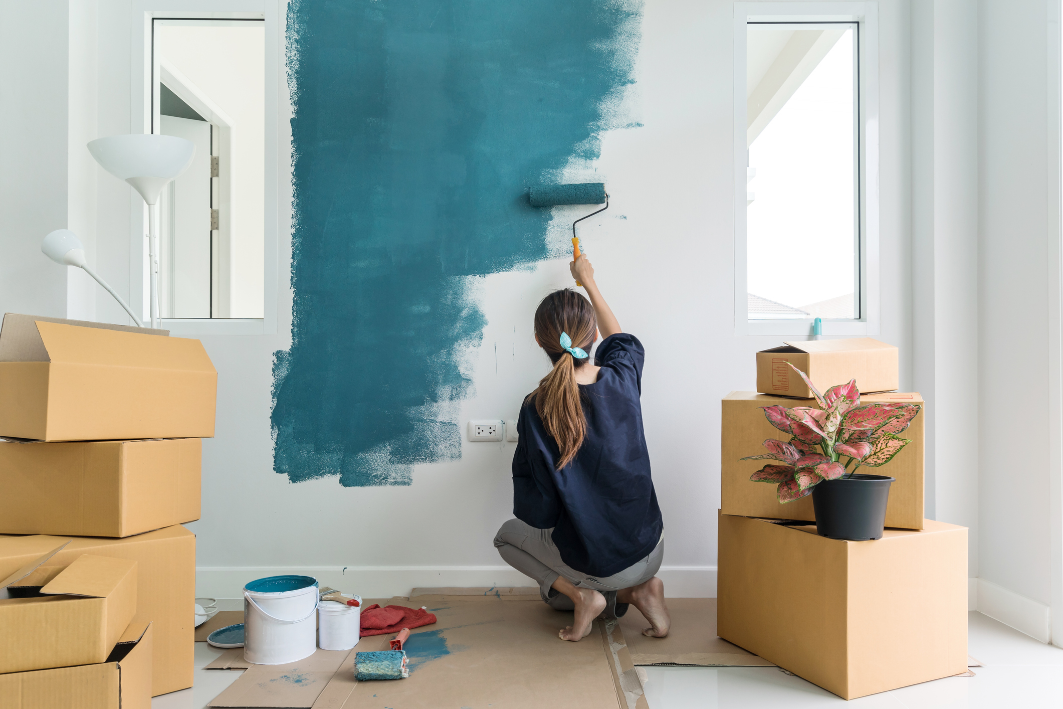 Young asian happy woman painting interior wall